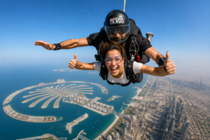 Tandem skydivers freefalling above Palm Jumeirah and Dubai skyline, showcasing the thrilling Sky Dive Dubai experience with professional safety equipment.
