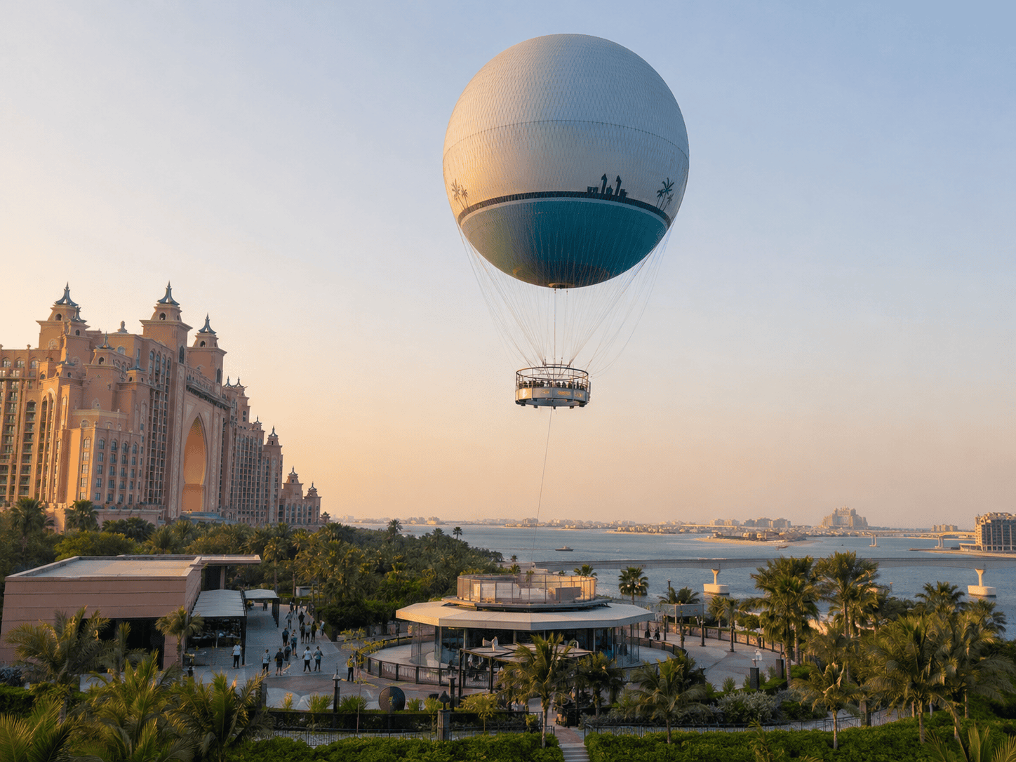The Dubai Balloon rising above Atlantis, The Palm at golden hour, with palm trees, waterfront views and Palm Jumeirah in the background.