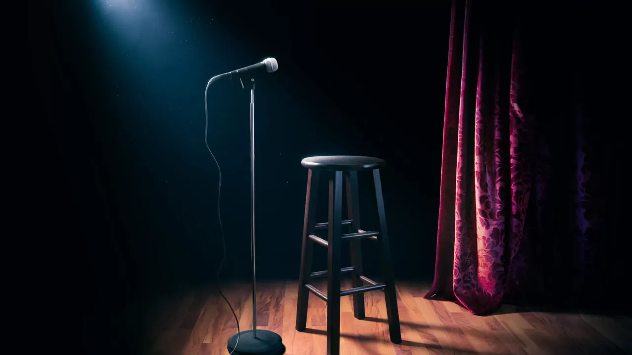 Microphone and stool on a comedy club stage under a spotlight