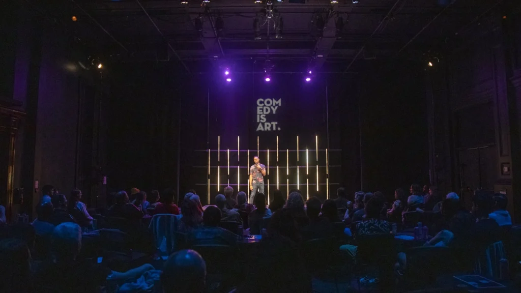 Comedian performing live on stage in front of a packed crowd at the Dubai Comedy Festival
