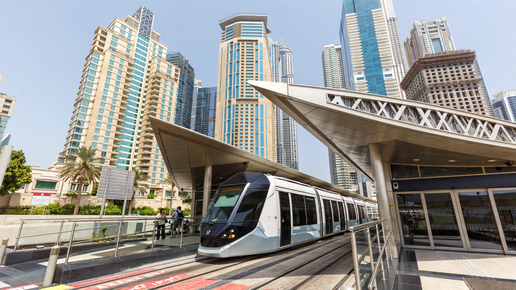 Dubai Tram arriving at a marina station with hotel towers behind
