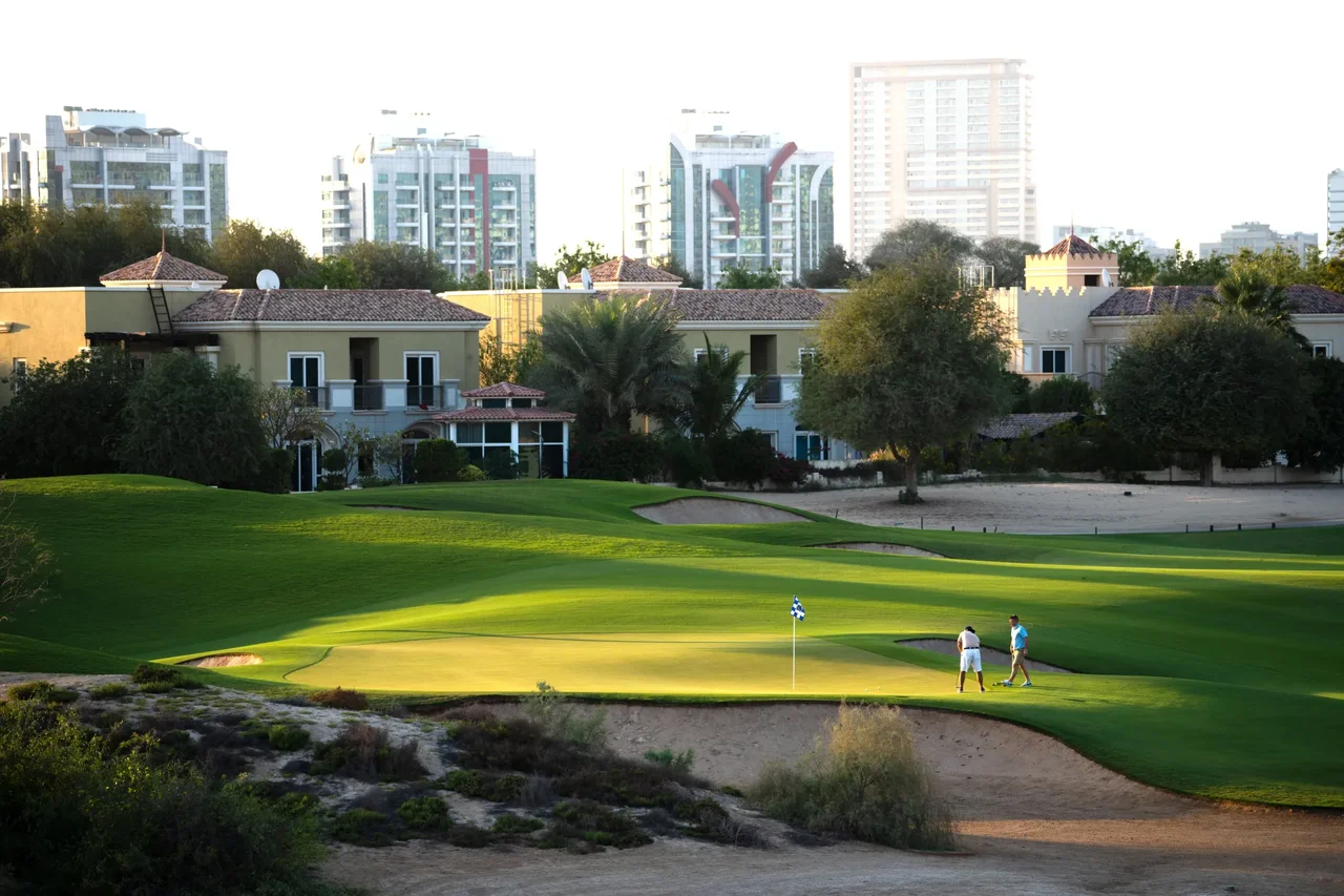 Golfers putting on the green at The Els Club desert-links course in Dubai Sports City