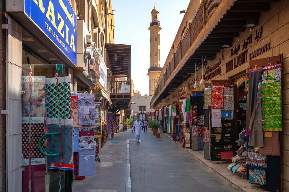 Fabric stalls lining a shaded lane in the Textile Souk, Bur Dubai